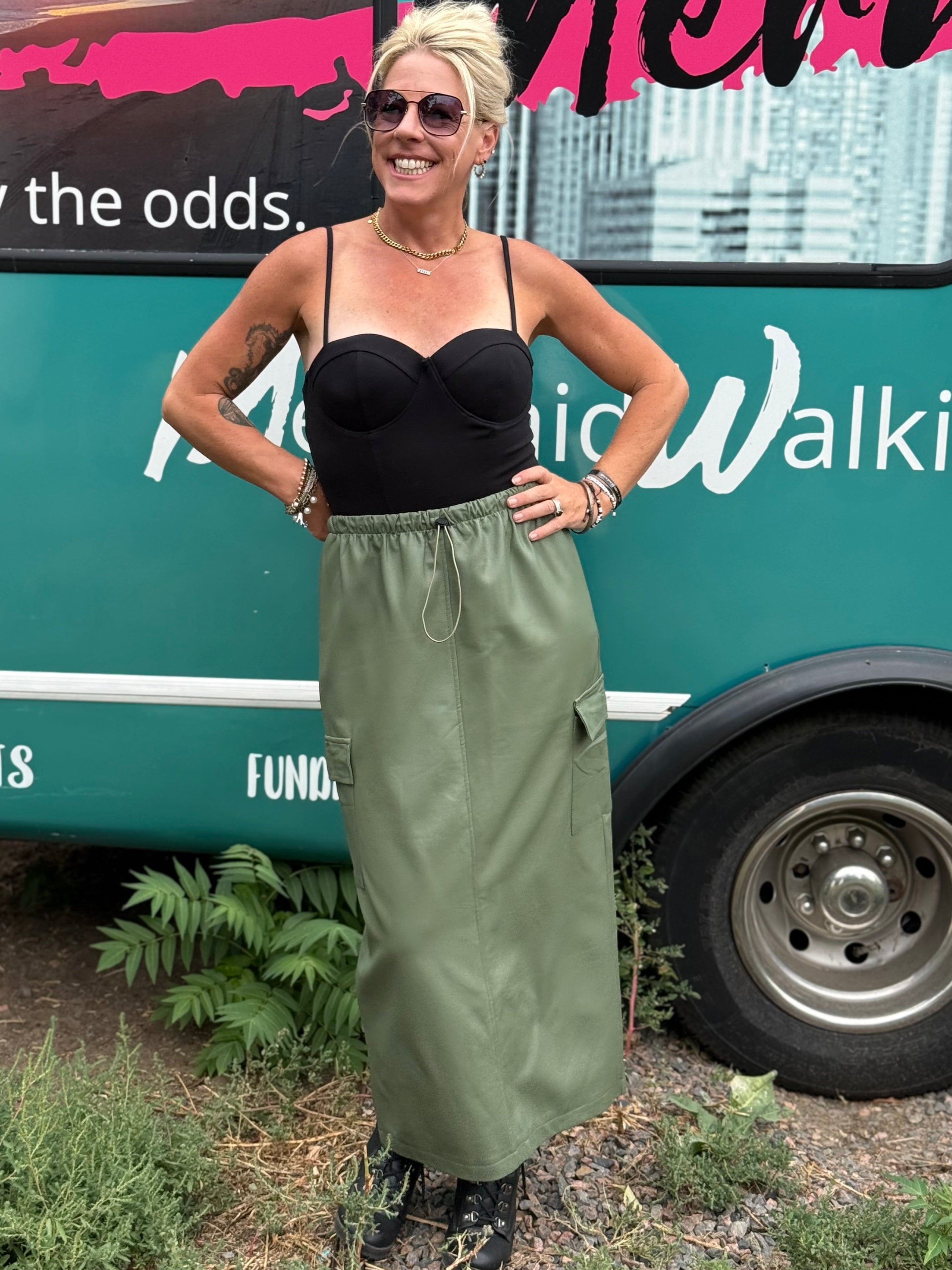 Woman standing in front of a green bus with text and branding.
