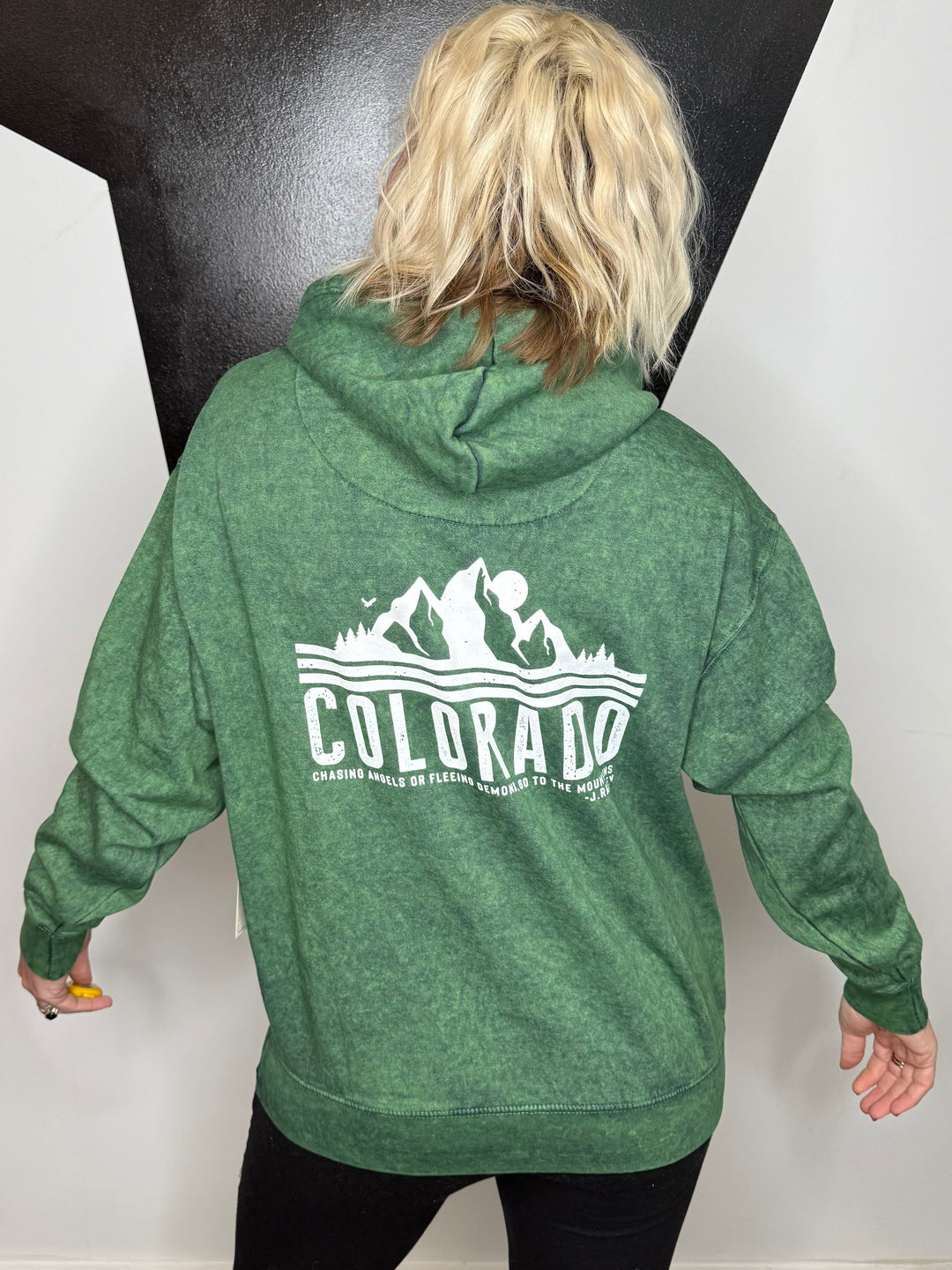 Person wearing a green sweatshirt with a logo on a black and white floor.