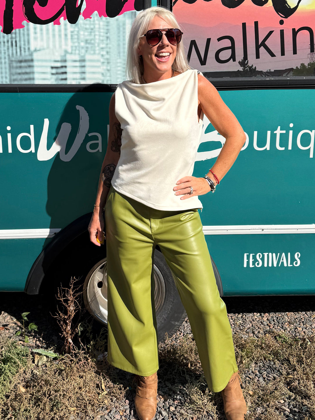 A woman posing outdoors in front of a teal bus with &