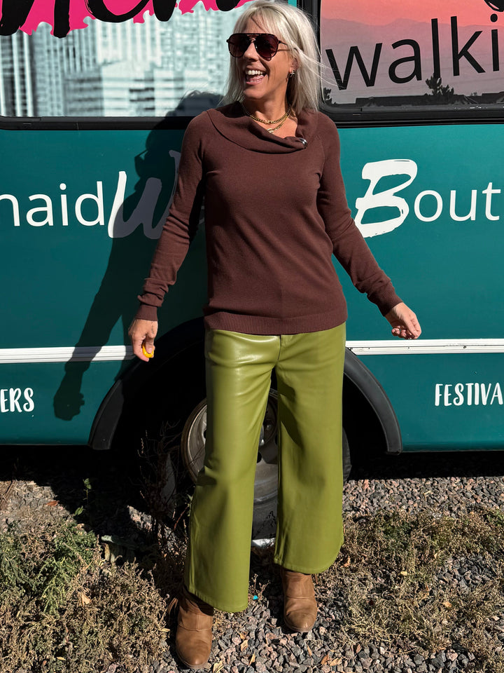A woman stands in front of a teal bus with &