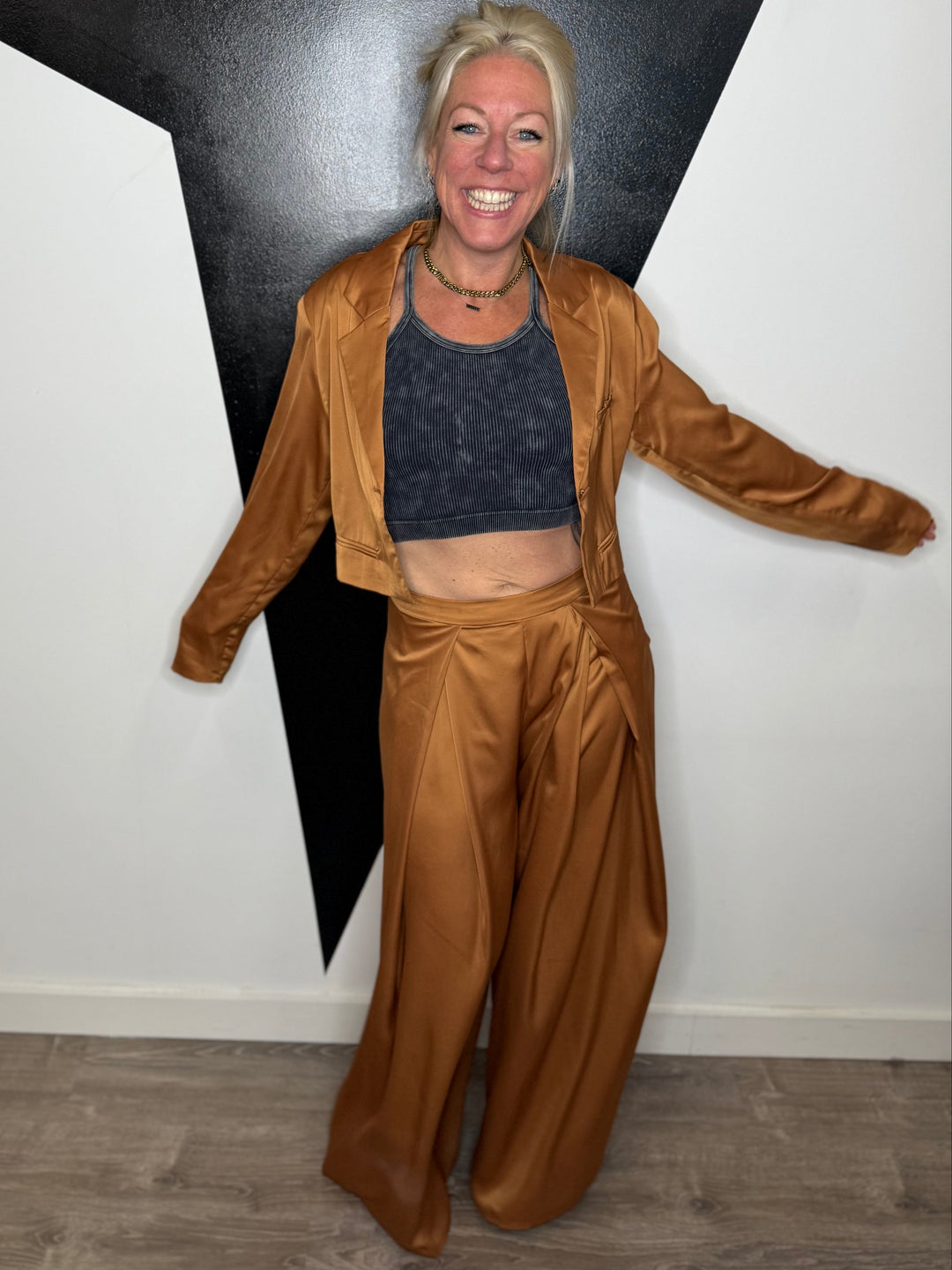 Person wearing a brown outfit standing against a black and white wall.