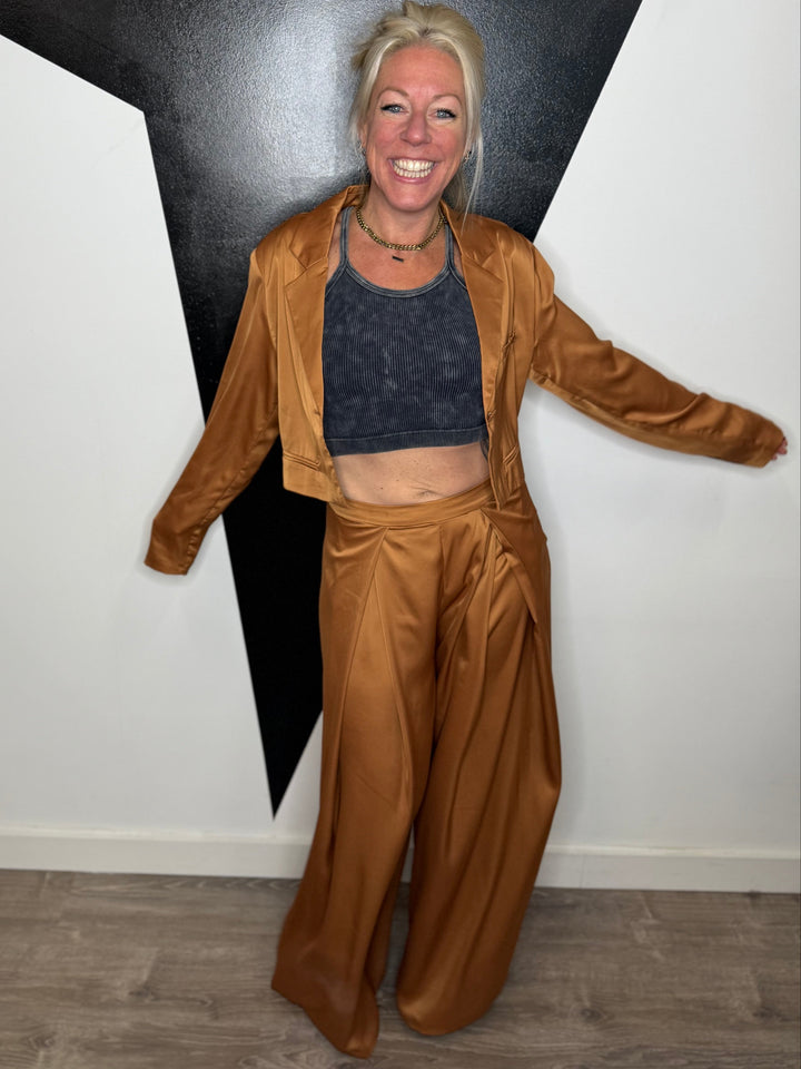 Person wearing a brown outfit standing against a black and white wall.