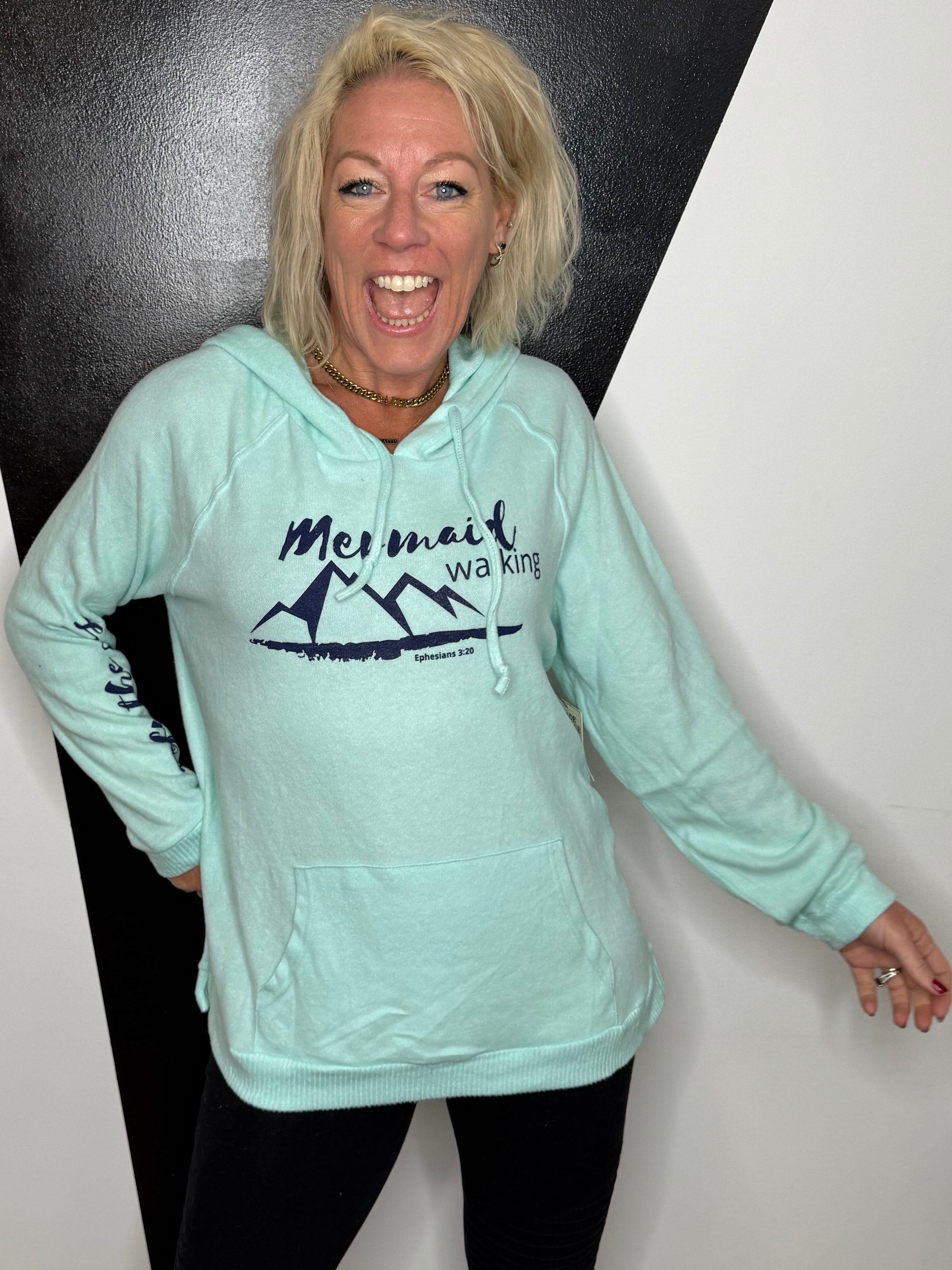 Person wearing a light blue hoodie with a logo on a black and white floor.