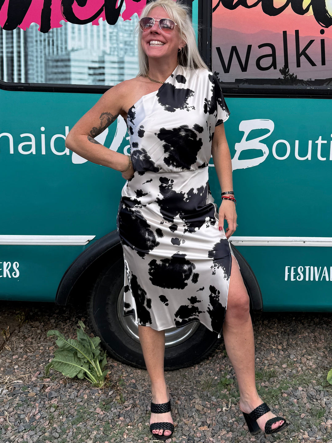 Woman in a black and white dress standing next to a turquoise bus with 'Mermaid Walking Boutique' branding.