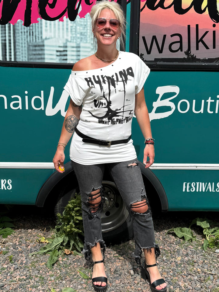 A woman stands in front of a teal mobile boutique bus with &