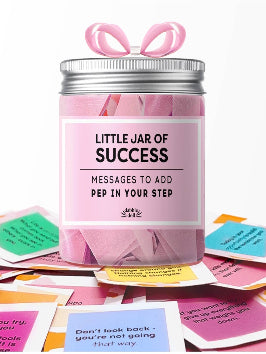 Jar labeled 'Little Jar of Success' with pink lid and scattered cards on a white background