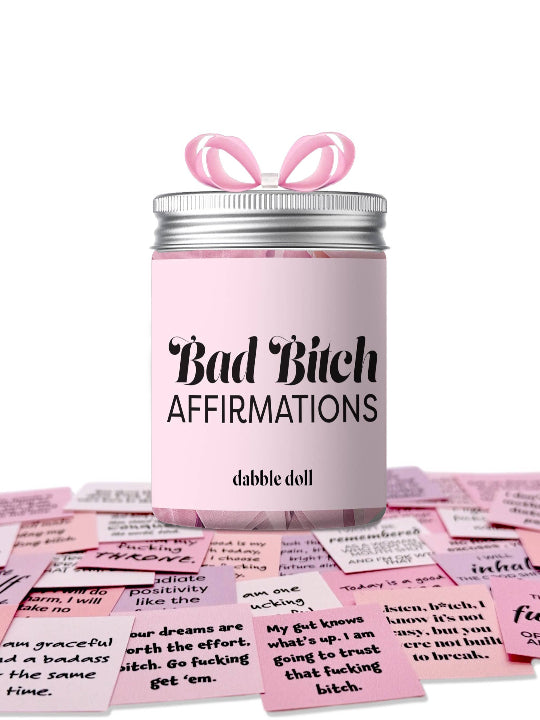 Pink jar labeled 'Bad Bitch Affirmations' by dabble doll with pink cards on a white background