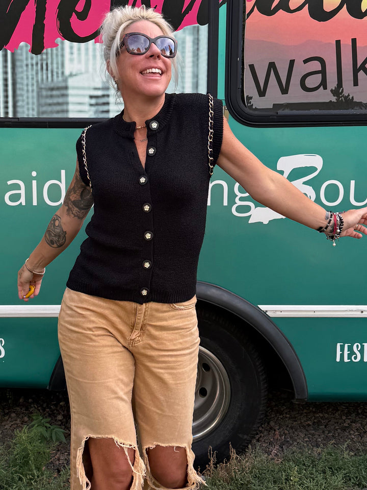 A woman stands in front of a teal bus with &