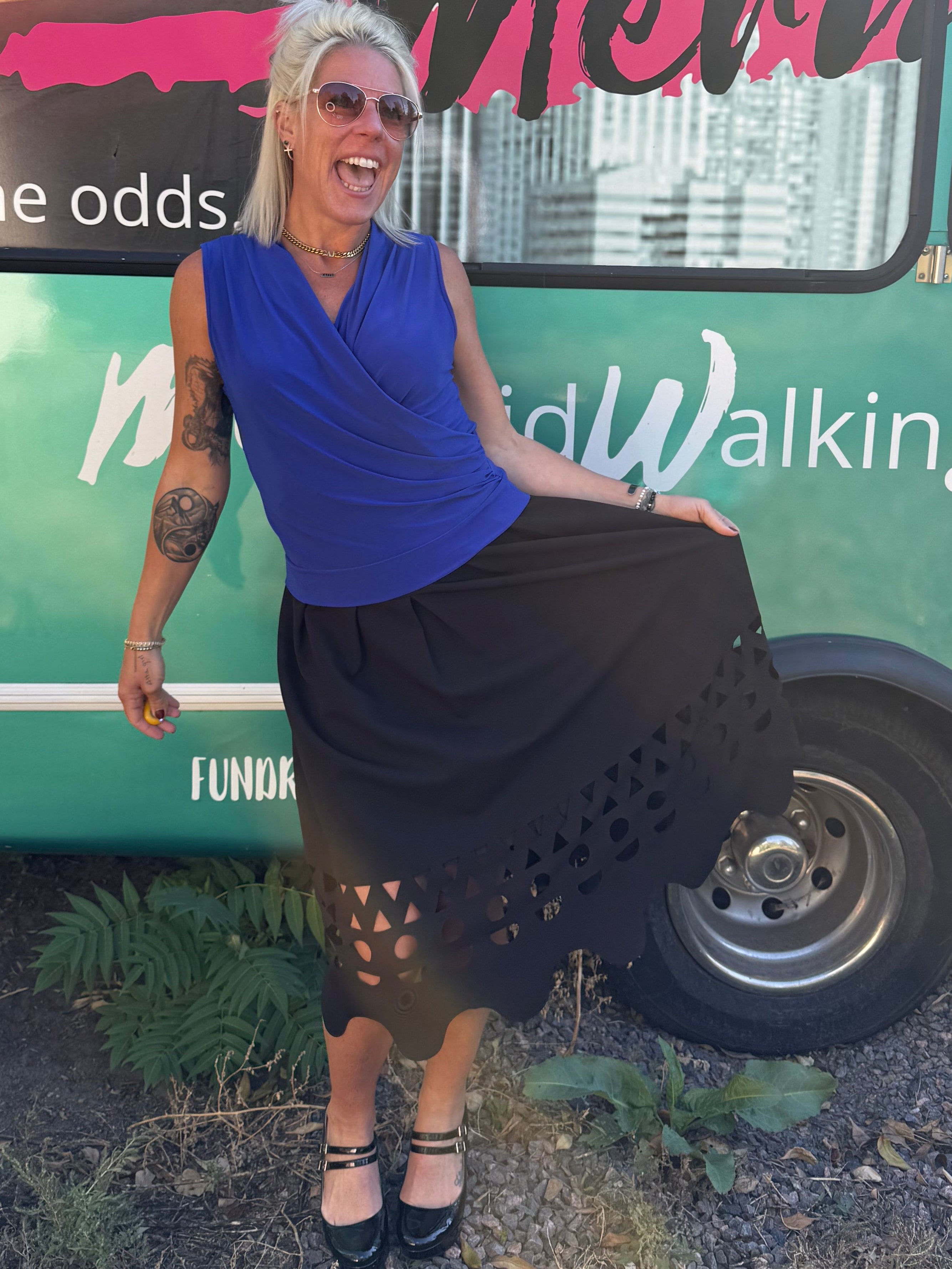 Person standing next to a large green and black vehicle with text and graphics on a natural background