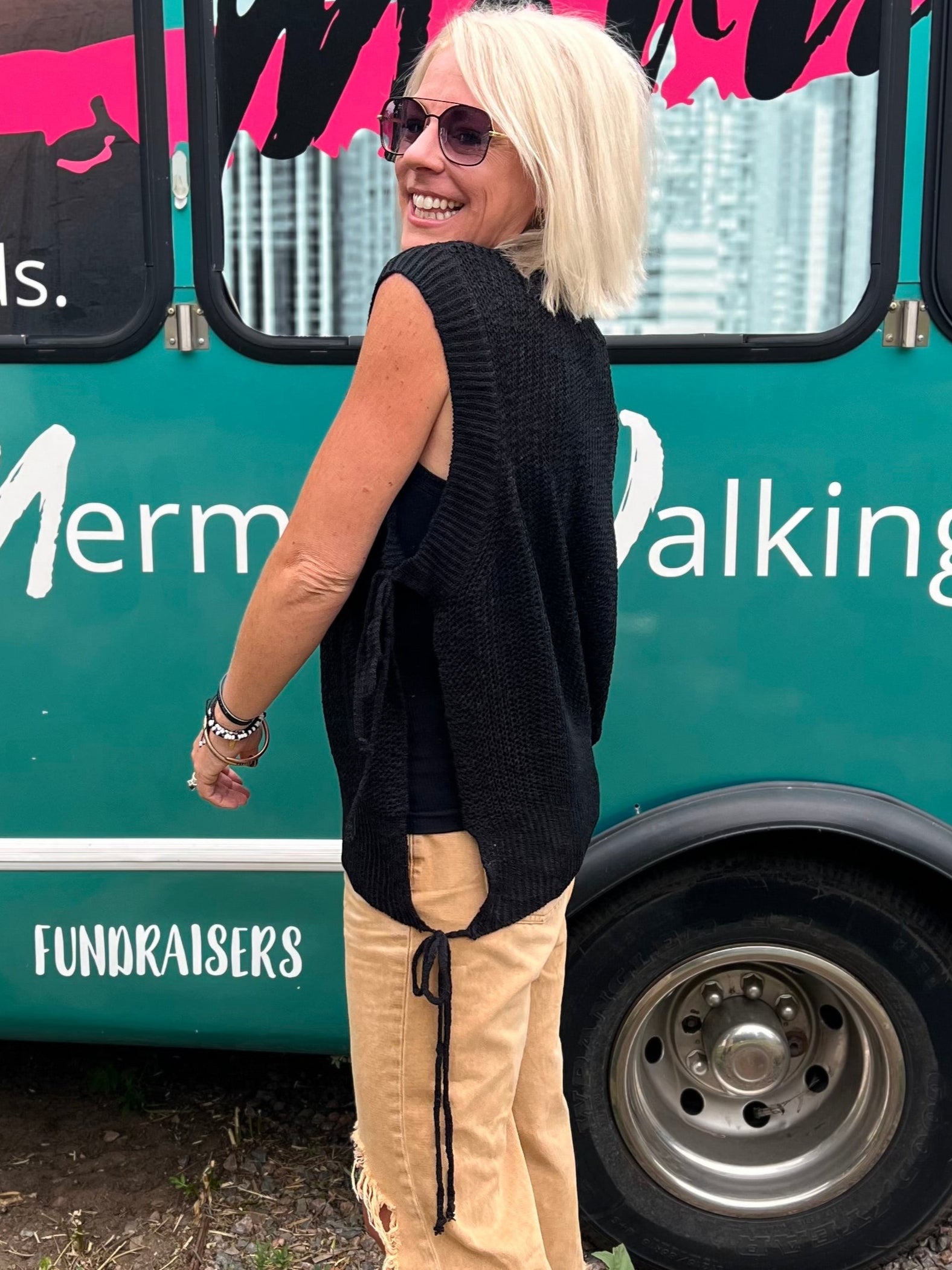 Woman standing in front of a teal bus with 'Mermaid Walking Boutique' branding.