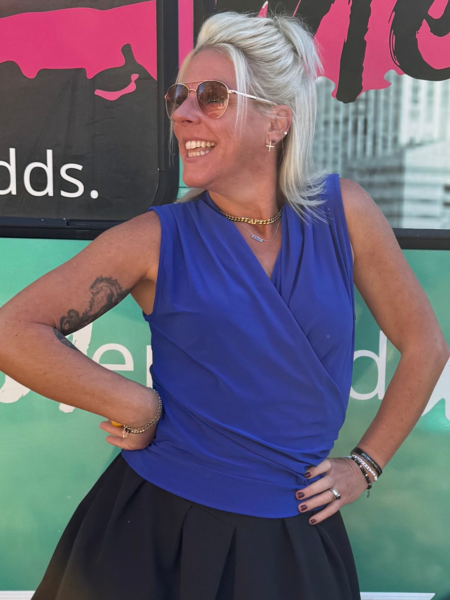 Woman posing in front of a colorful bus with text on a grassy background