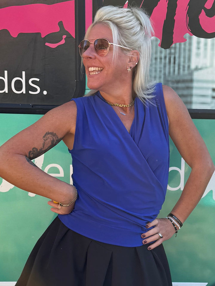 Woman posing in front of a colorful bus with text on a grassy background