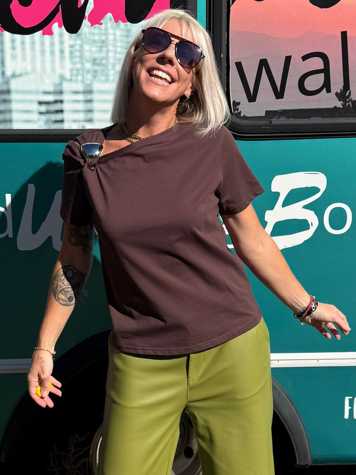 A woman posing in front of a teal bus with &