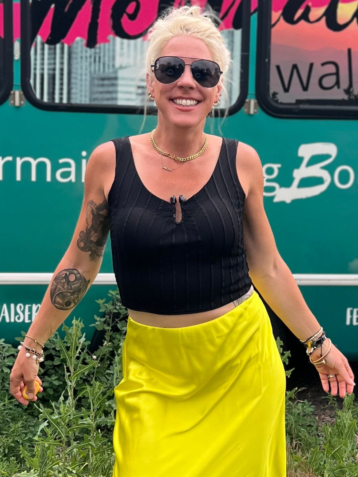Woman in a yellow skirt standing in front of a mobile boutique bus.