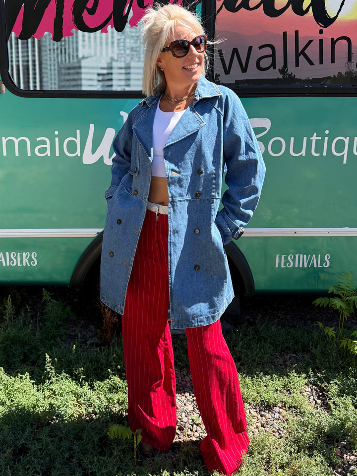 A woman stands outdoors in front of a teal bus with &