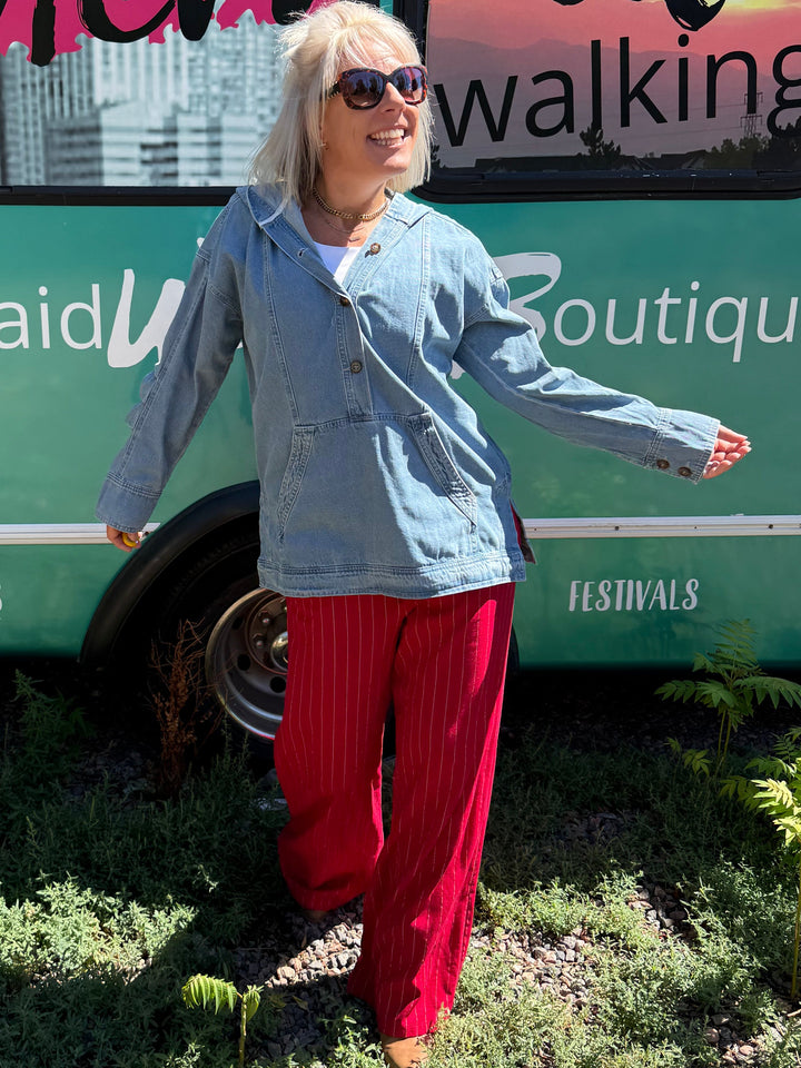 A woman with blonde hair and sunglasses stands outdoors in front of a green bus with &