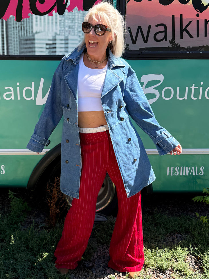 A woman stands outdoors in front of a teal bus with &