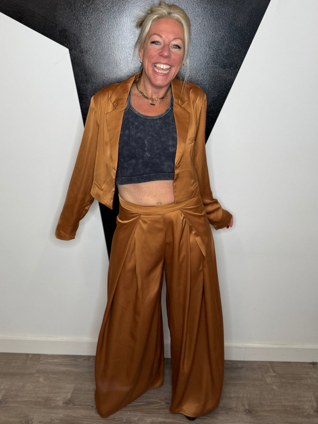 Person wearing a brown outfit standing against a black and white wall.