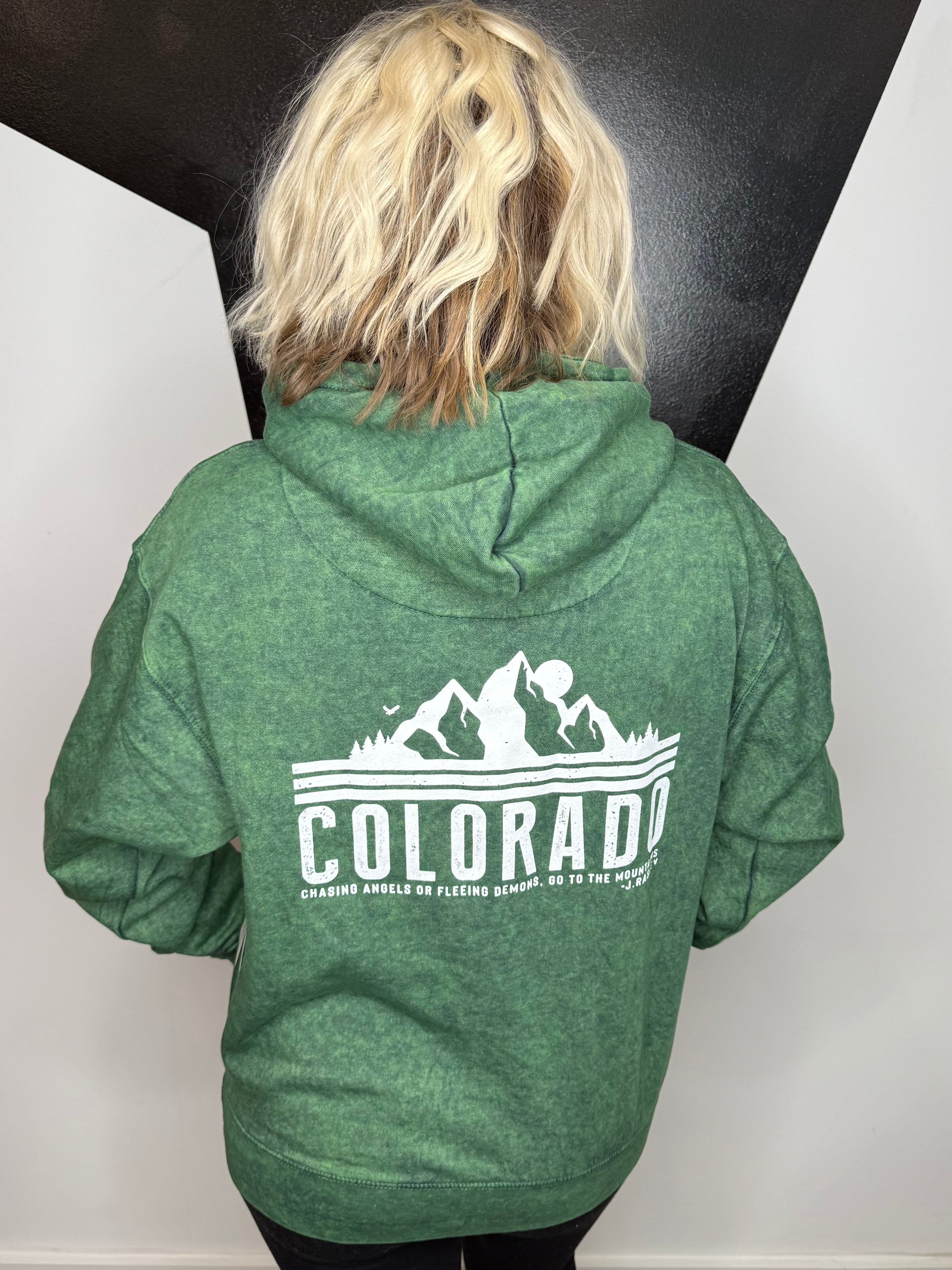 Person wearing a green hoodie with 'Colorado' printed on it, standing on a black and white floor.