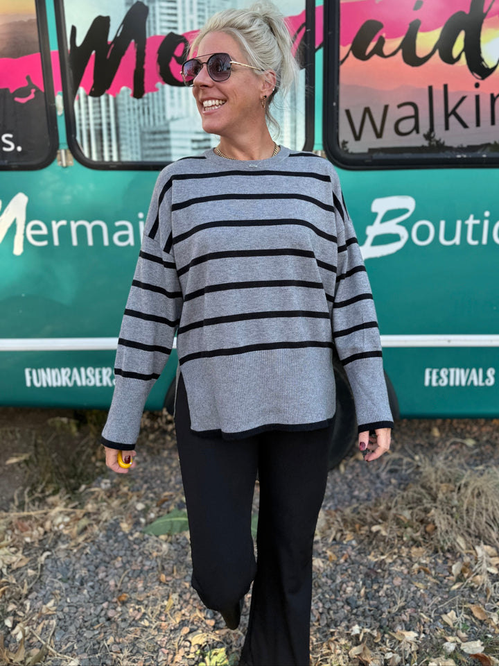 Woman wearing a striped sweater standing in front of a bus with &