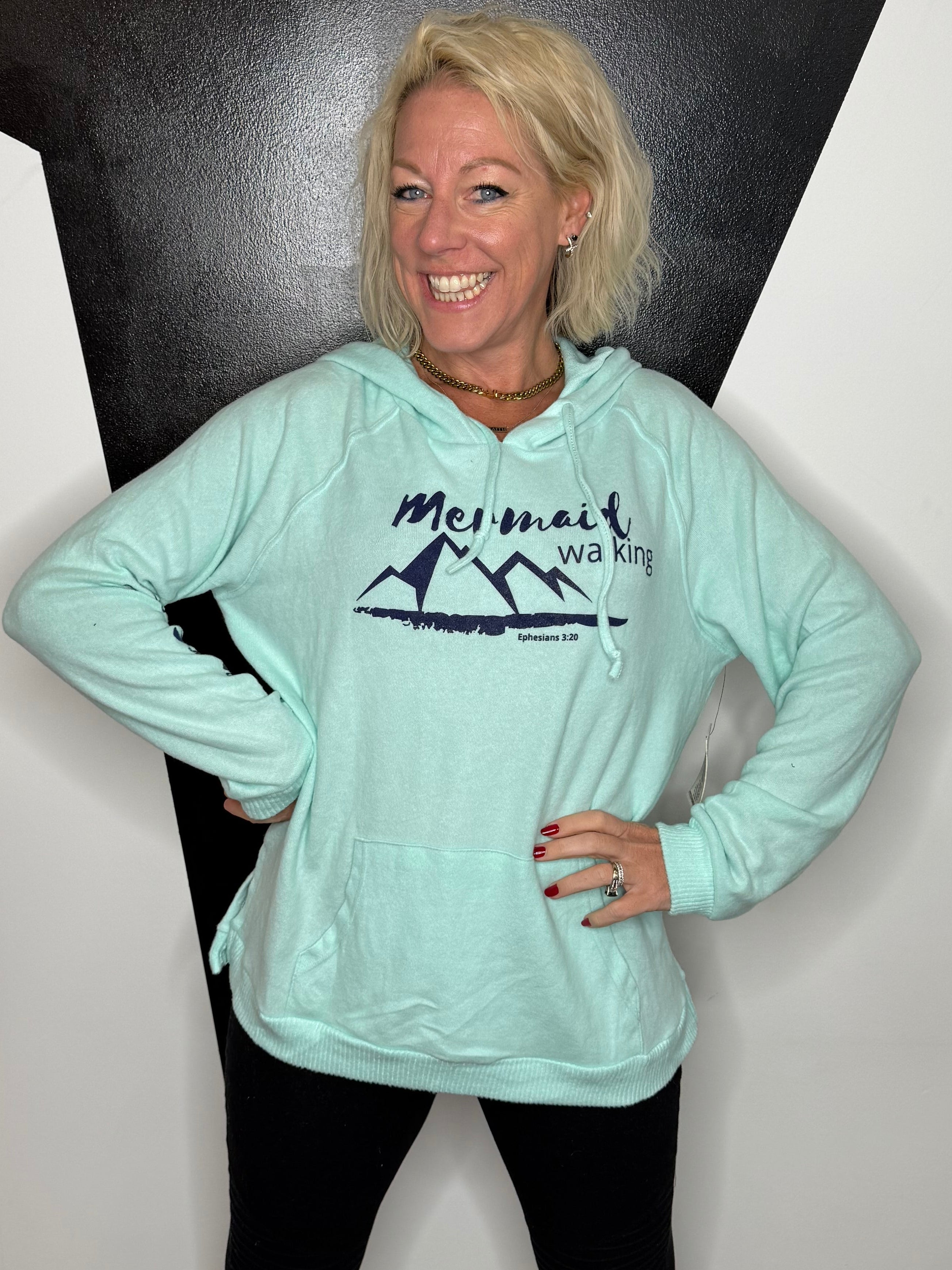 Person wearing a light blue sweatshirt with text and graphics on a white and black floor.