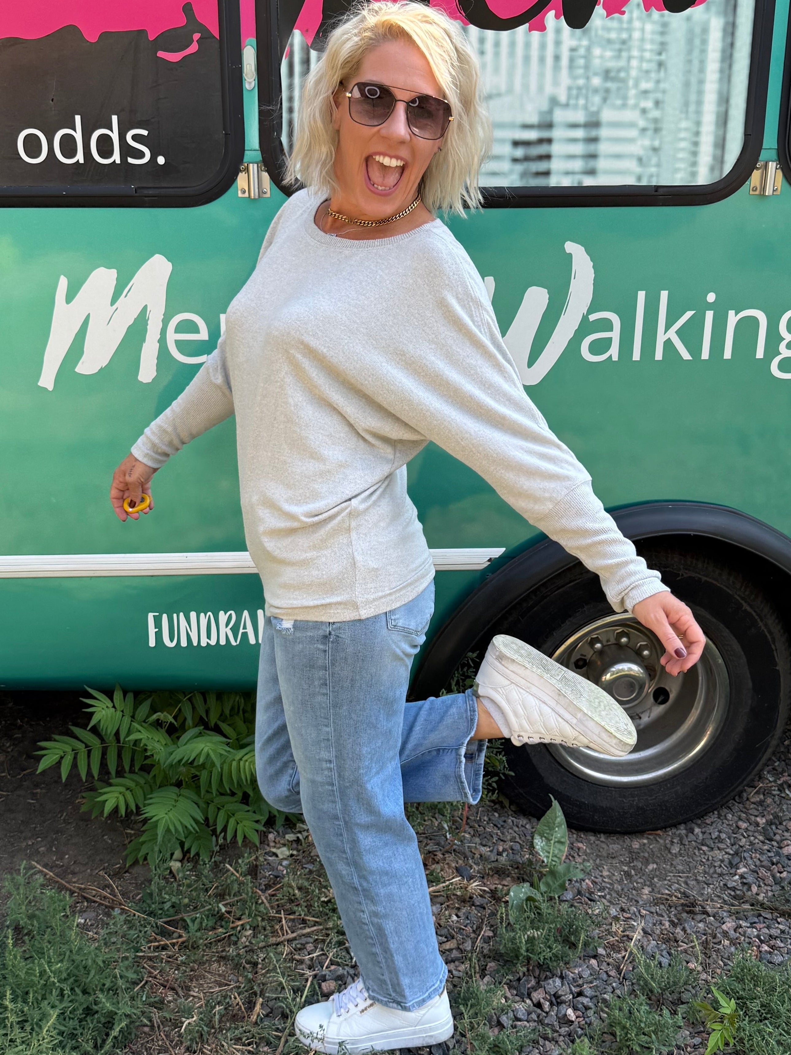 Person standing next to a green bus with text on a street.