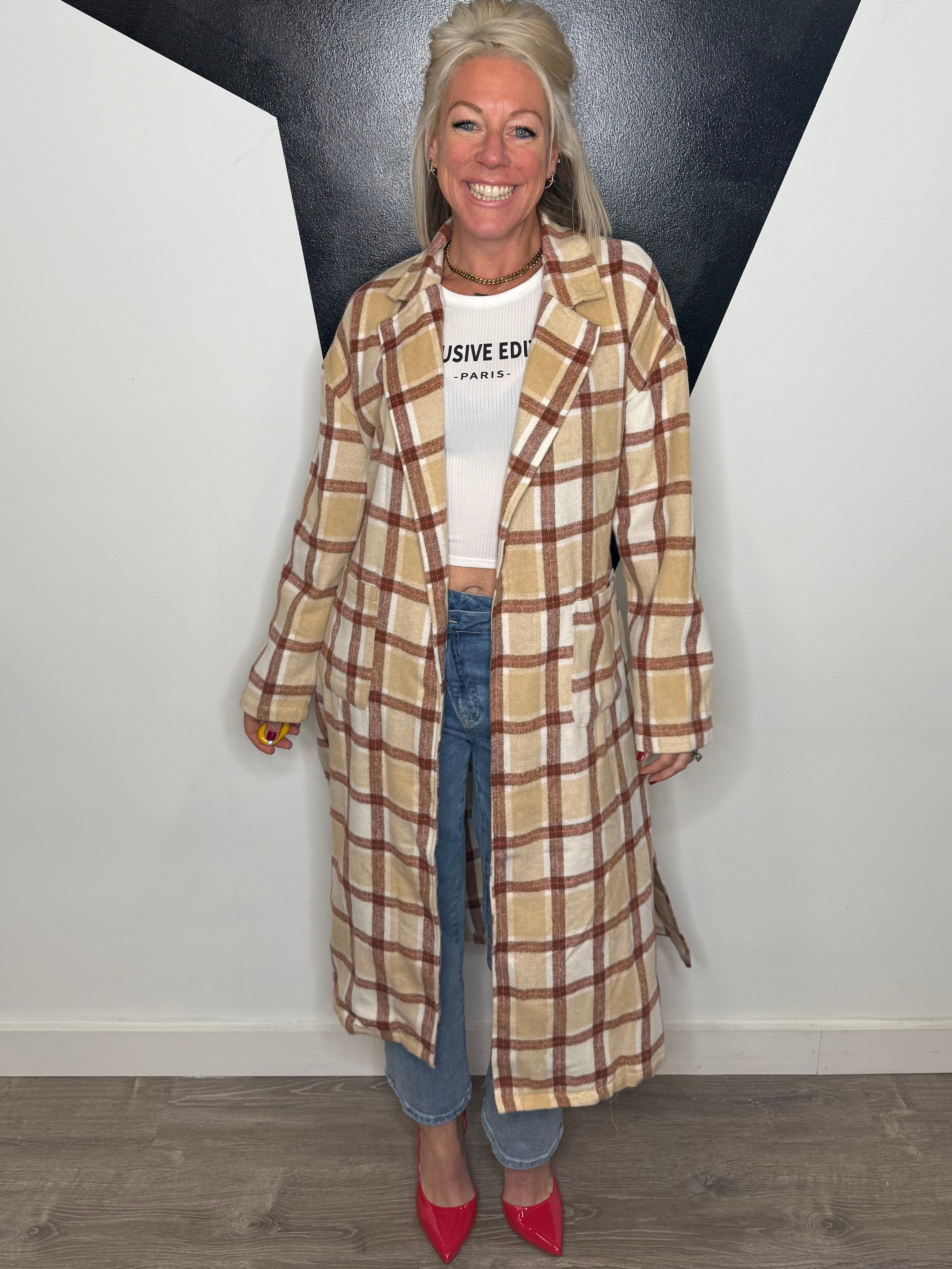 Person wearing a plaid coat standing on a black and white floor.