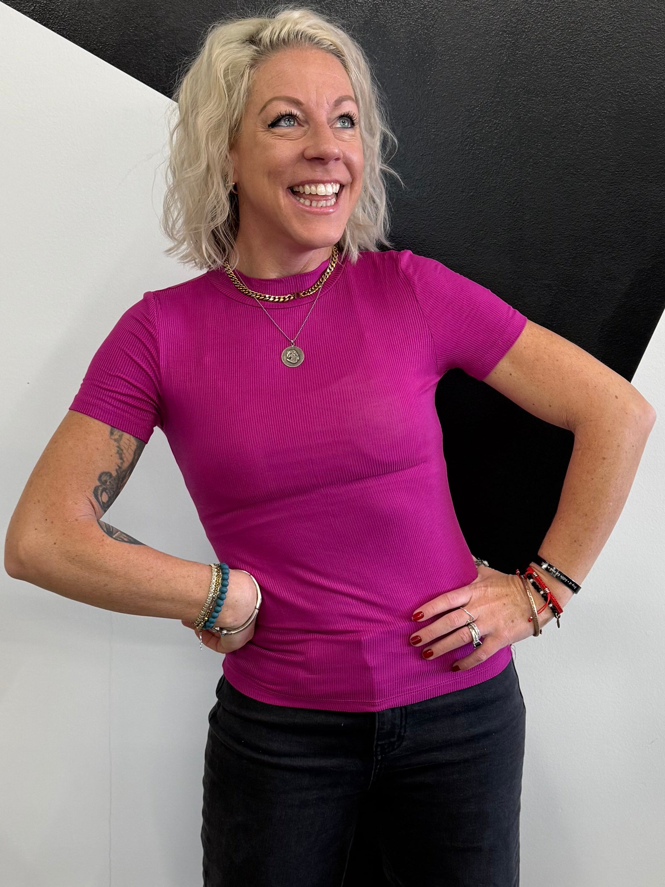 Person in a purple shirt and black pants standing on a black and white floor.