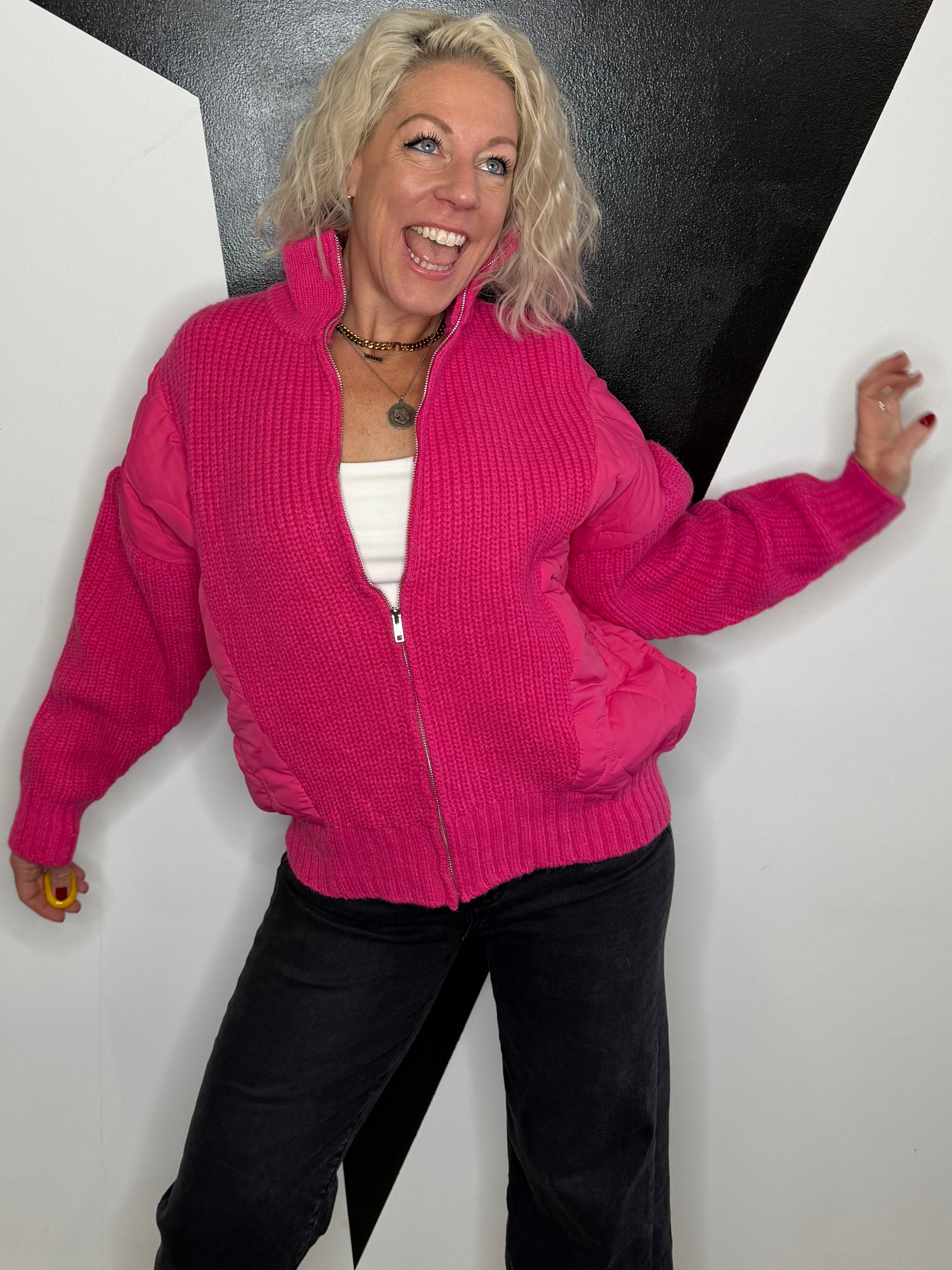 Person in a pink sweater and black pants standing on a white platform with a black floor.