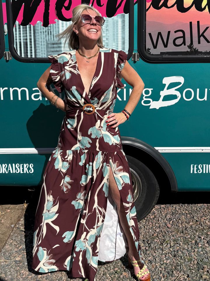 Woman in a patterned dress standing next to a bus with &