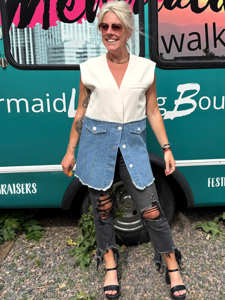 A woman stands in front of a teal mobile boutique bus with &