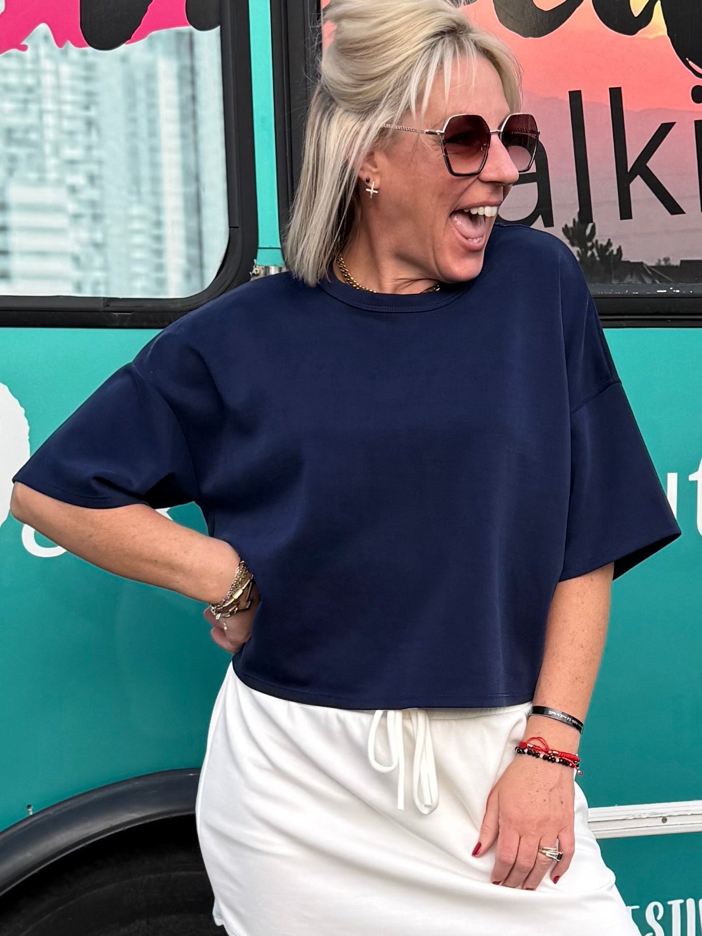 Person posing in front of a teal van with branding on a street.