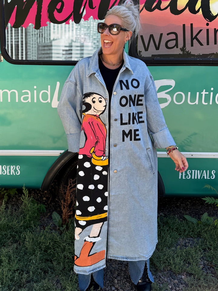 A woman stands outdoors in front of a turquoise bus with &