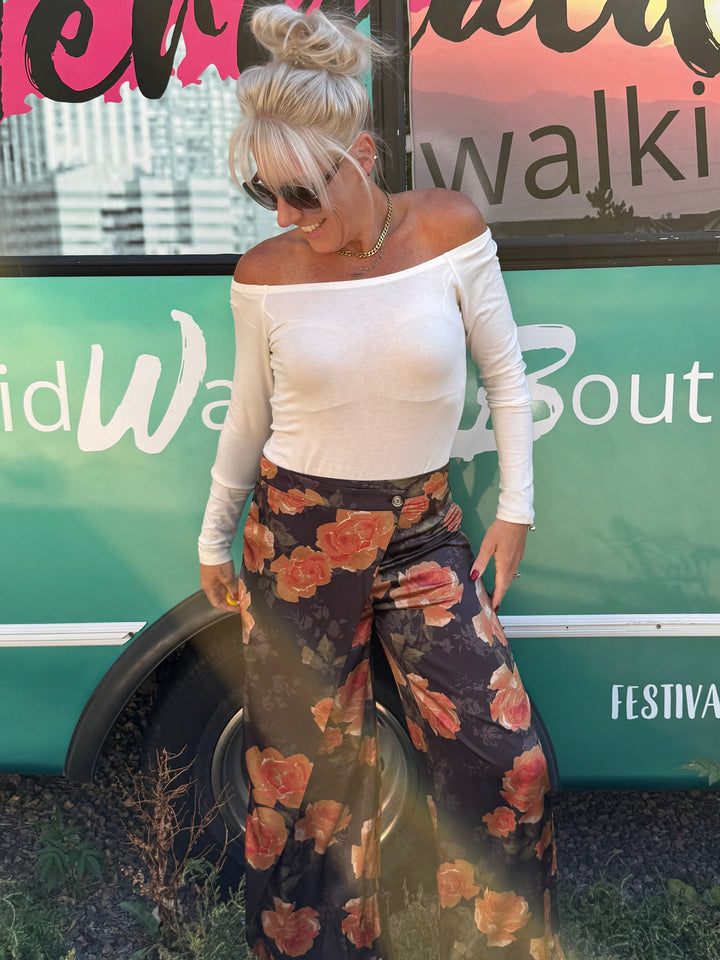 A woman stands outdoors in front of a teal bus with &
