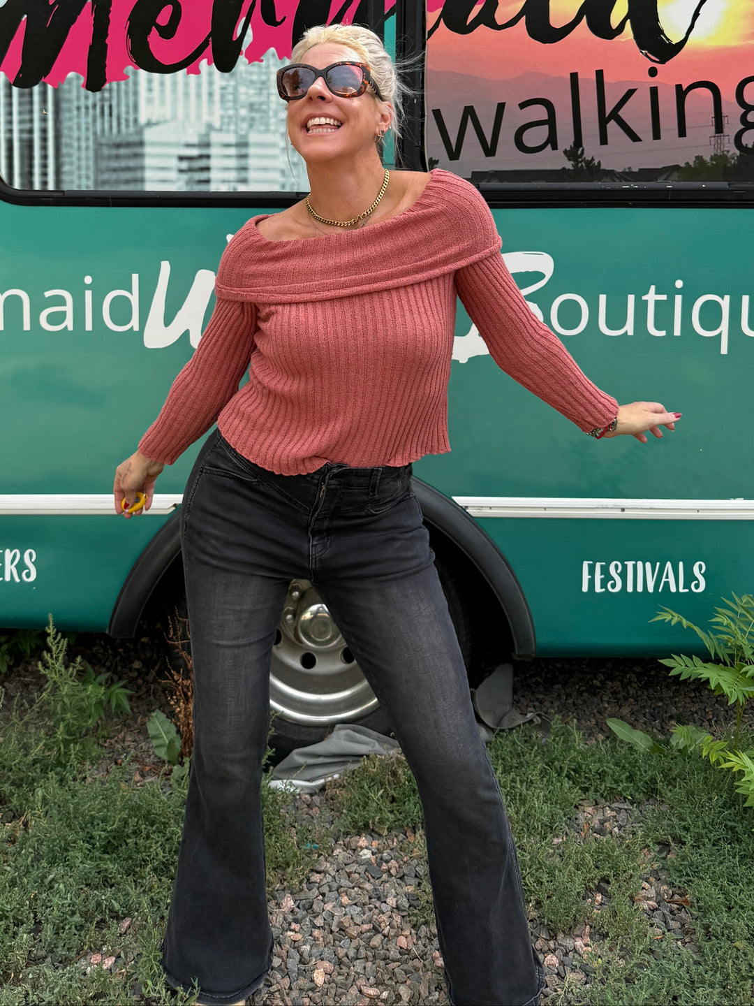 A woman posing outdoors in front of a teal trolley bus with &