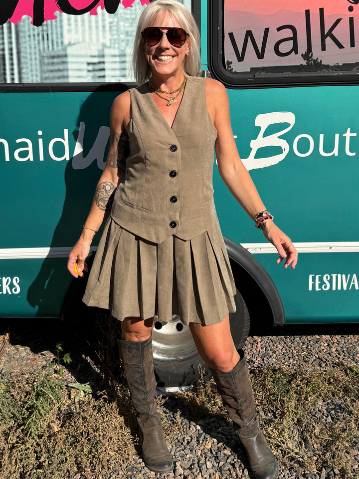 A woman stands outdoors in front of a teal bus with &