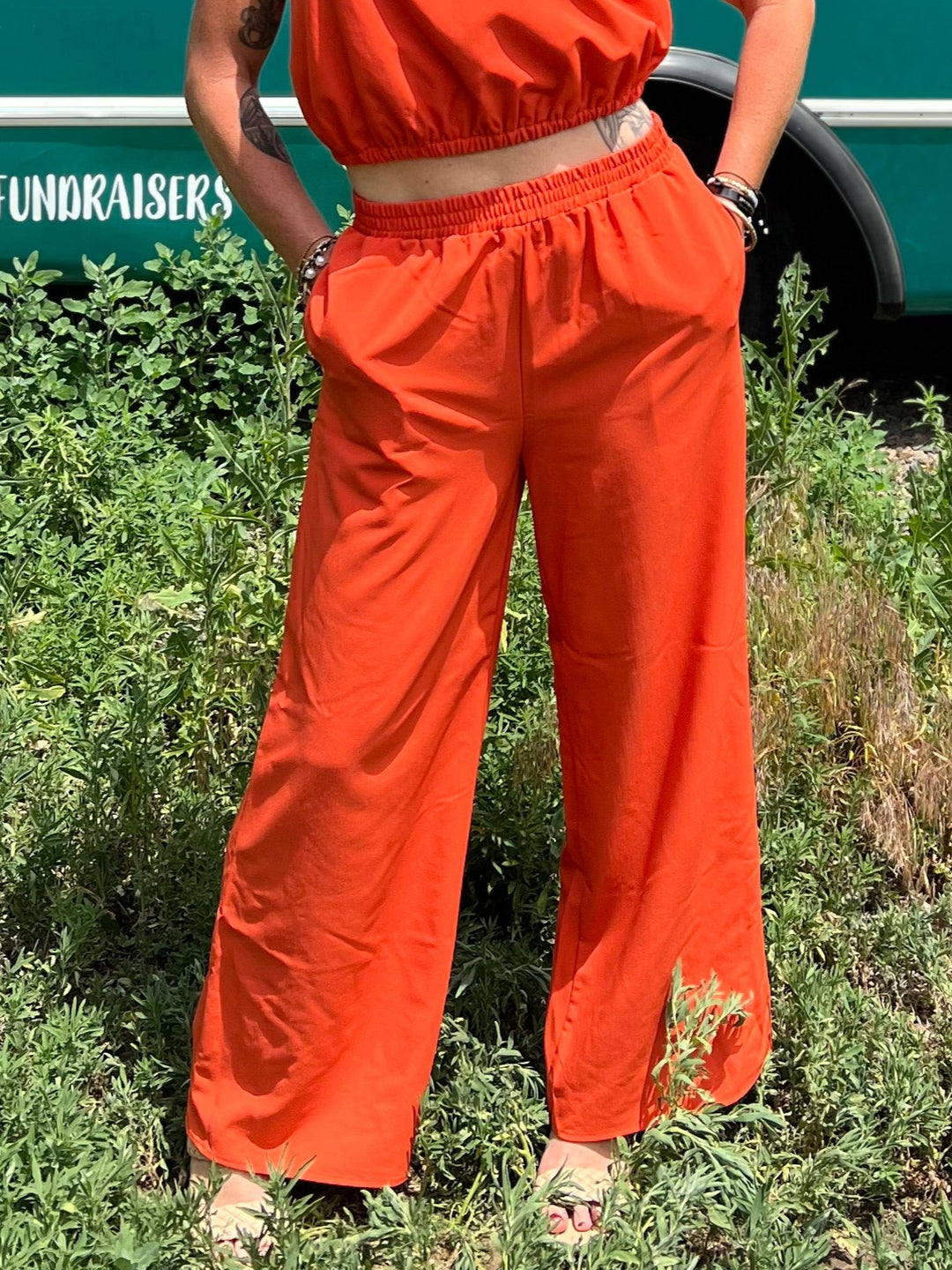 Woman in an orange outfit standing in front of a teal bus with 'Mermaid Walking' branding.