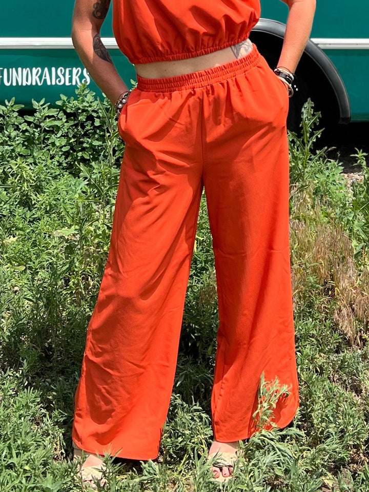 Woman in an orange outfit standing in front of a teal bus with &