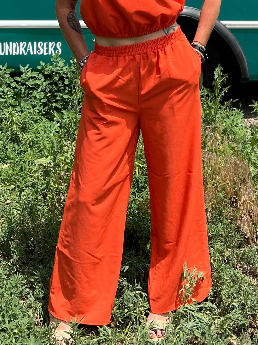Person in orange outfit standing in front of a teal bus with &