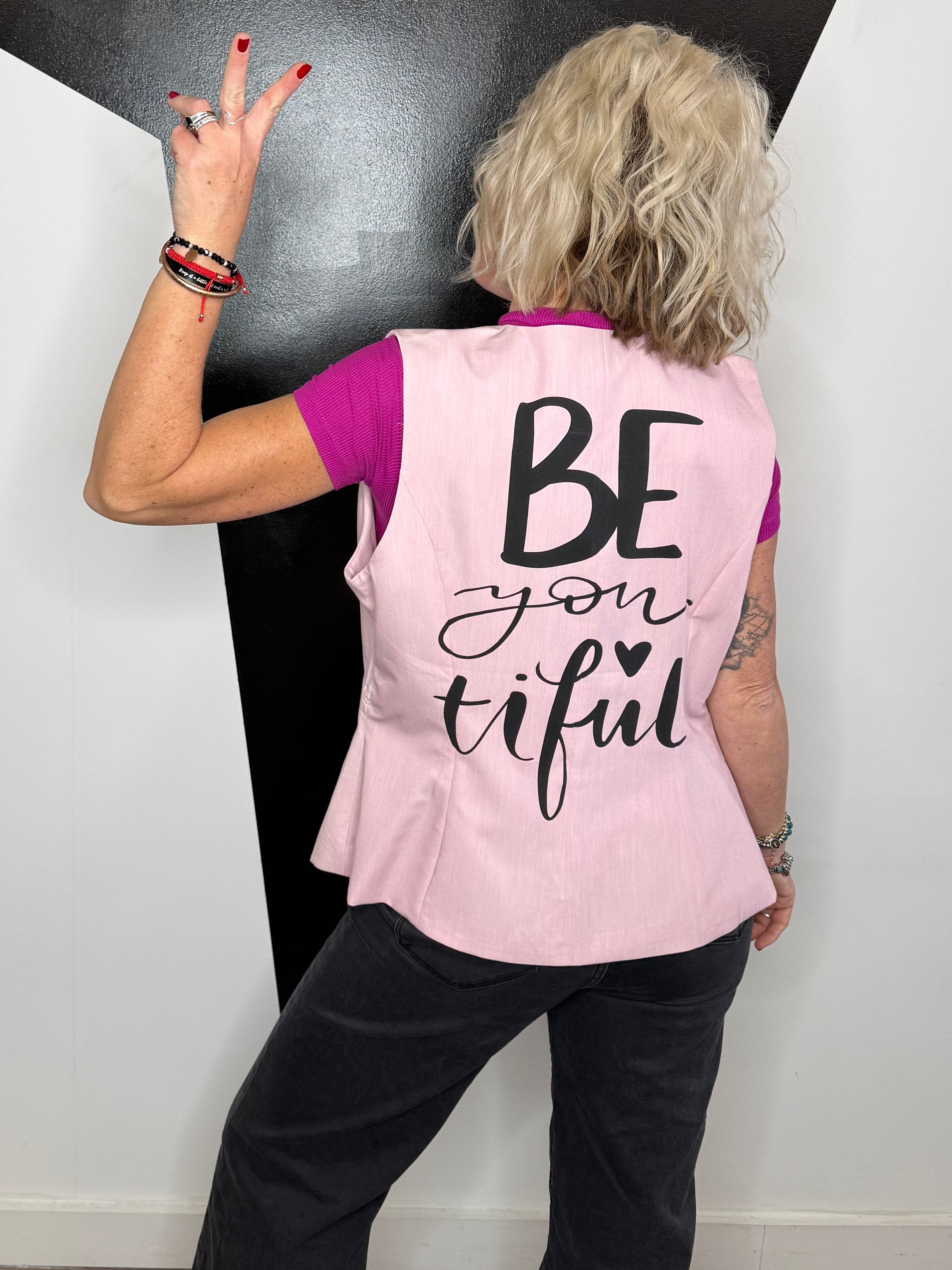 Person wearing a pink shirt with text, sitting on a black and white floor.