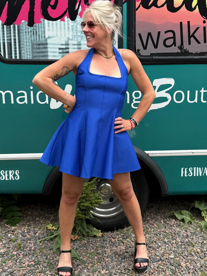 A woman posing in front of a teal mobile boutique bus with &