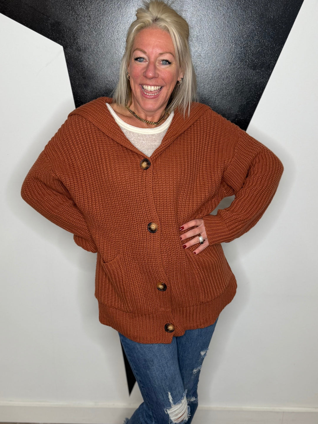 Woman wearing a brown cardigan with a black and white geometric wall background