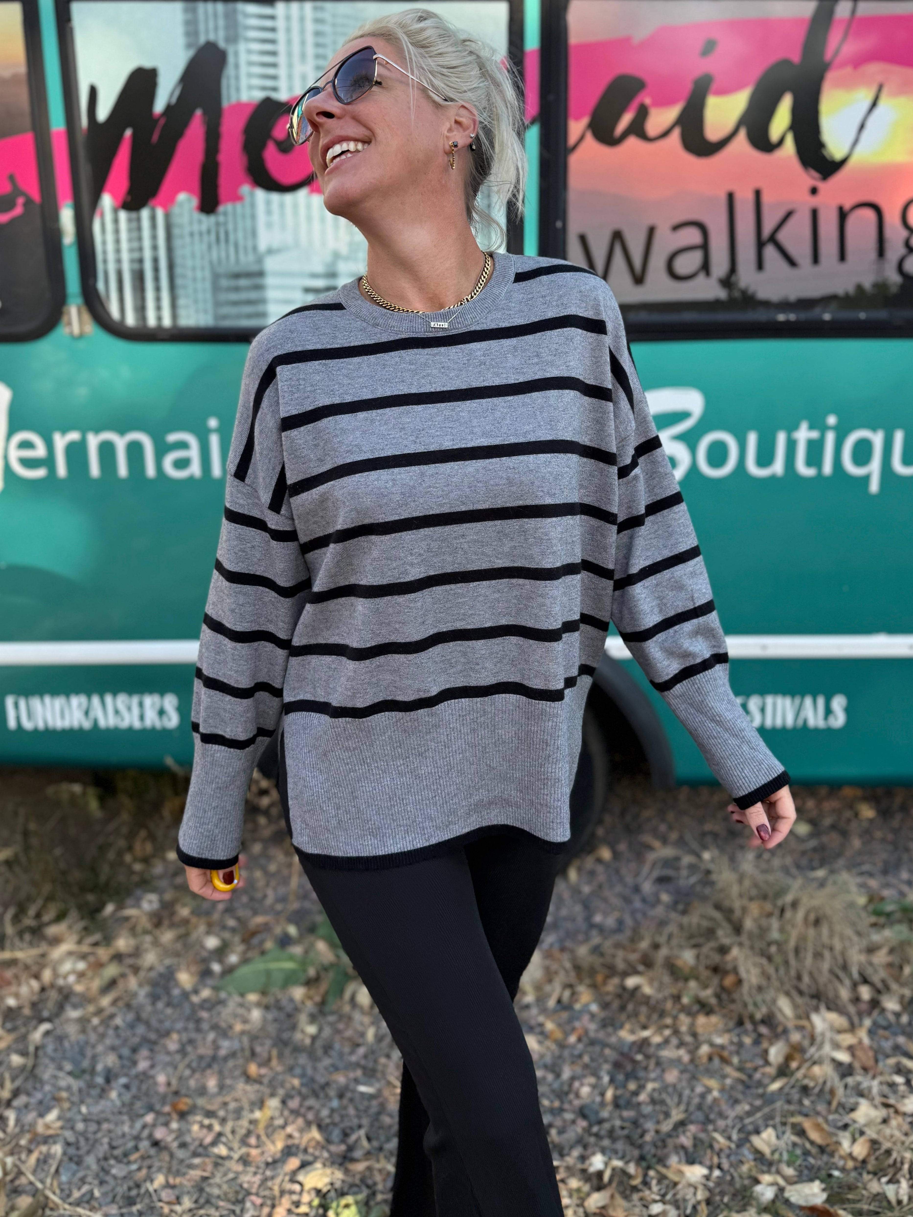 Woman in a striped sweater standing in front of a colorful bus with text.