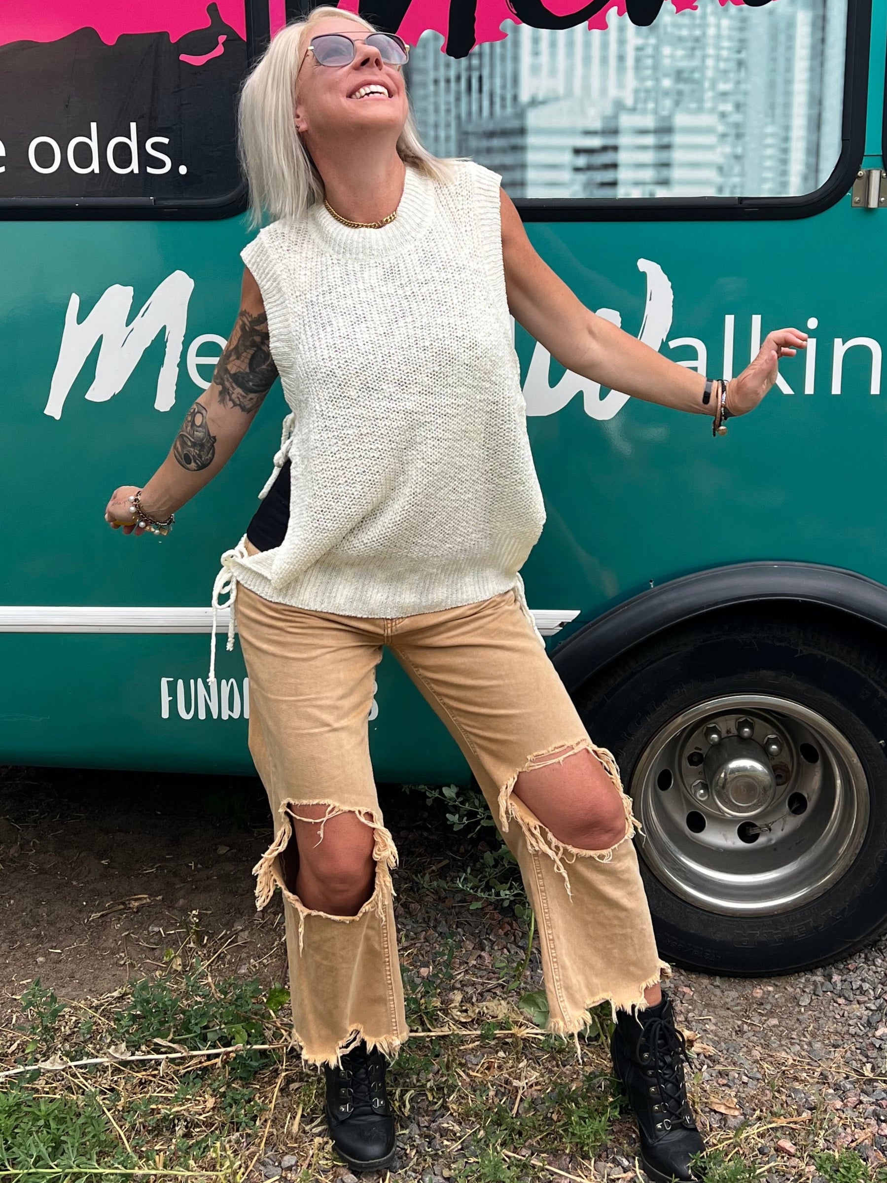 Person standing next to a teal bus with colorful graphics and text.