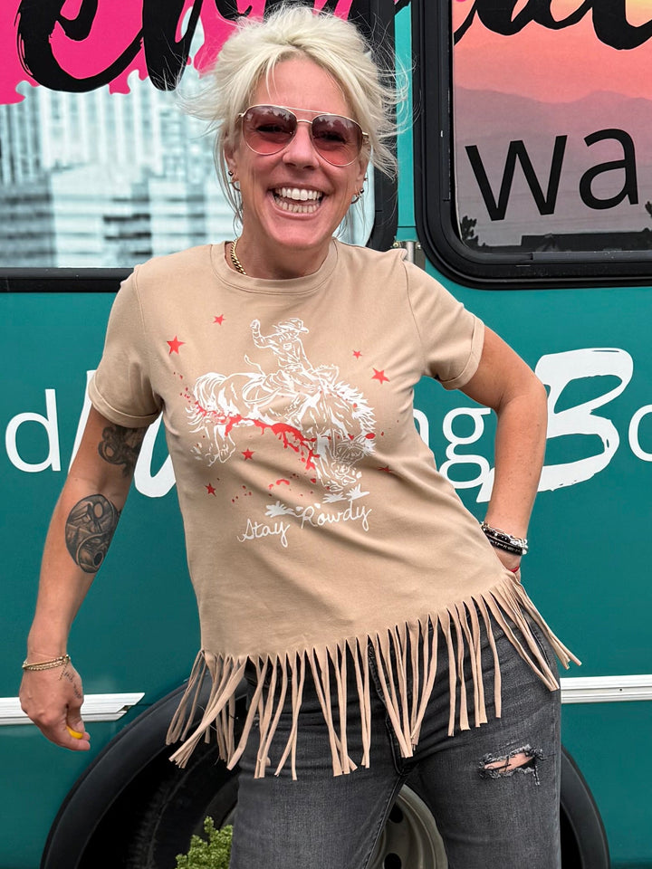 A woman stands in front of a teal mobile boutique bus with &