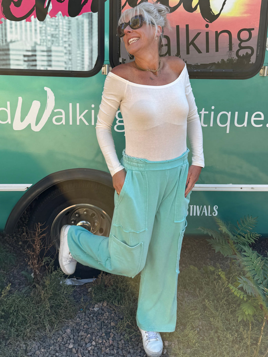 A woman posing in front of a teal bus with &