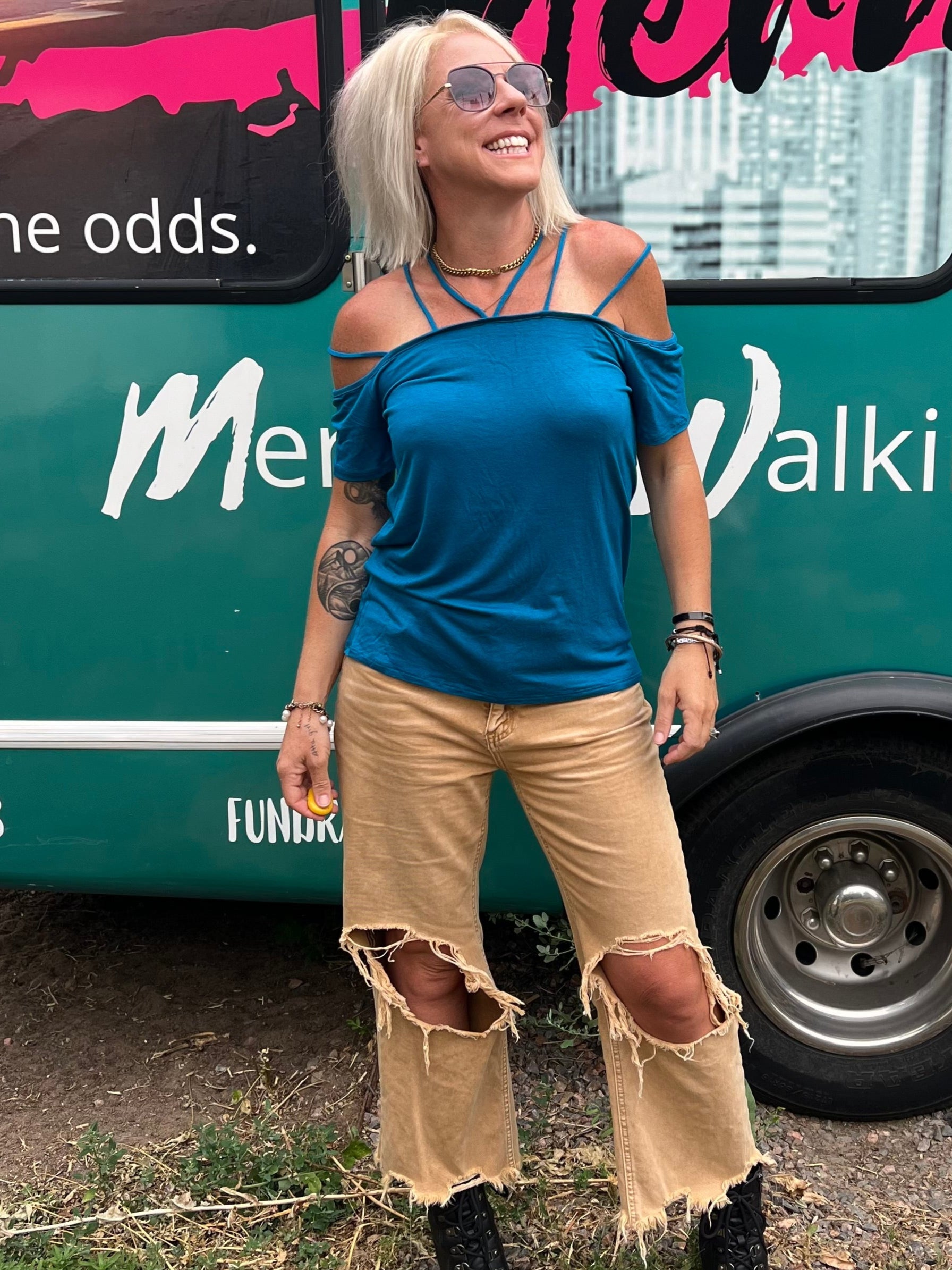 Woman standing in front of a teal bus with 'Mermaid Walking Bou' branding.
