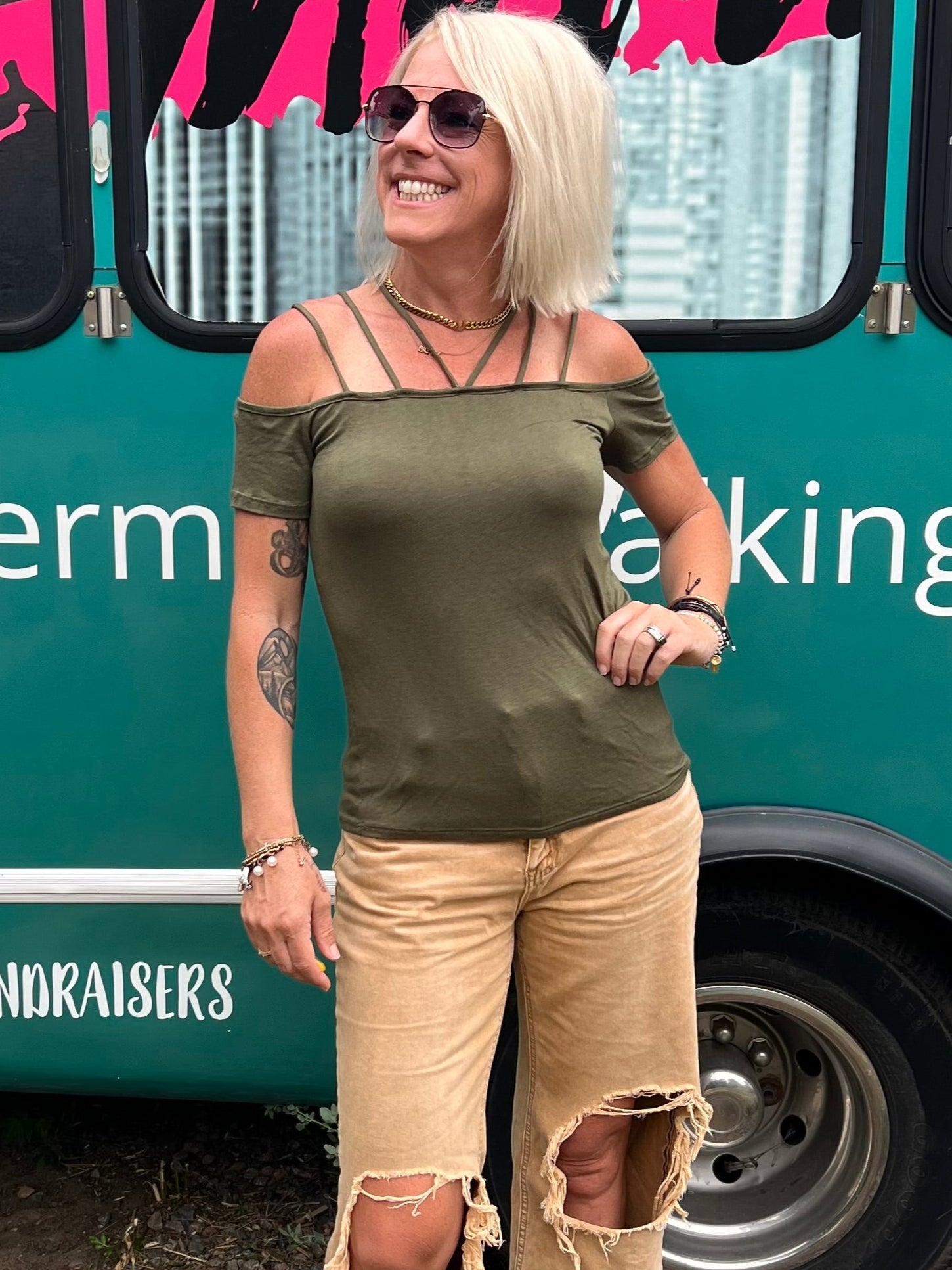 Woman standing in front of a teal bus with 'Mermaid Walking Boutique' branding.