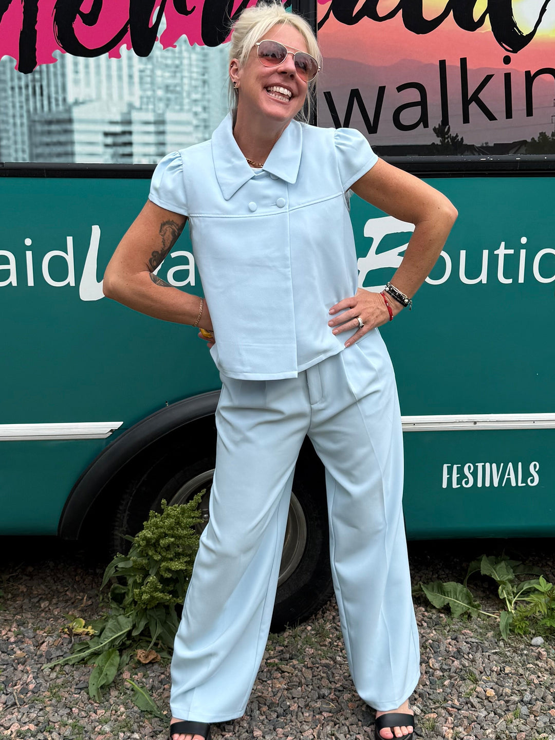 A woman posing in front of a teal bus with &