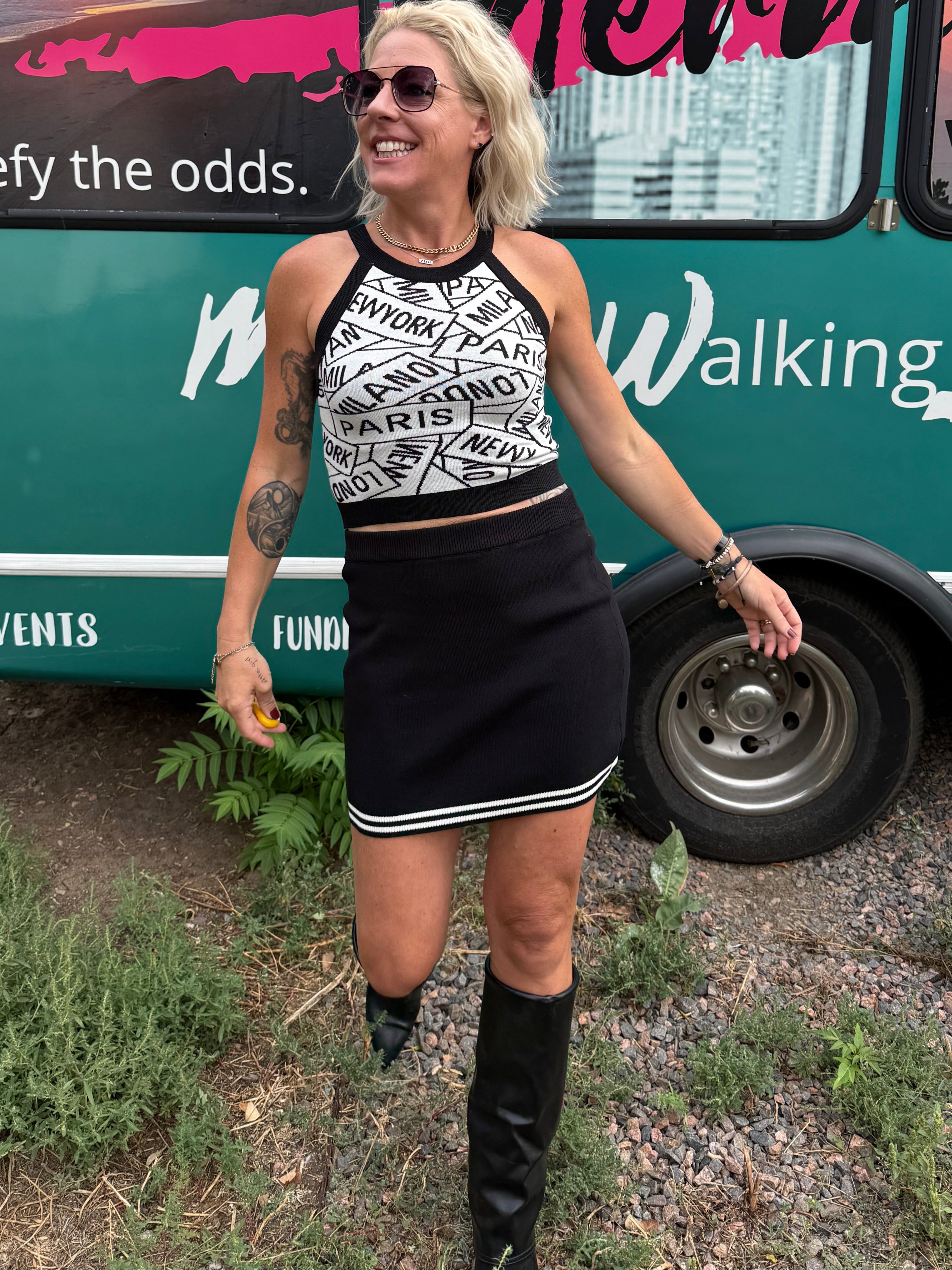 Person standing next to a teal bus with promotional graphics on a grassy area